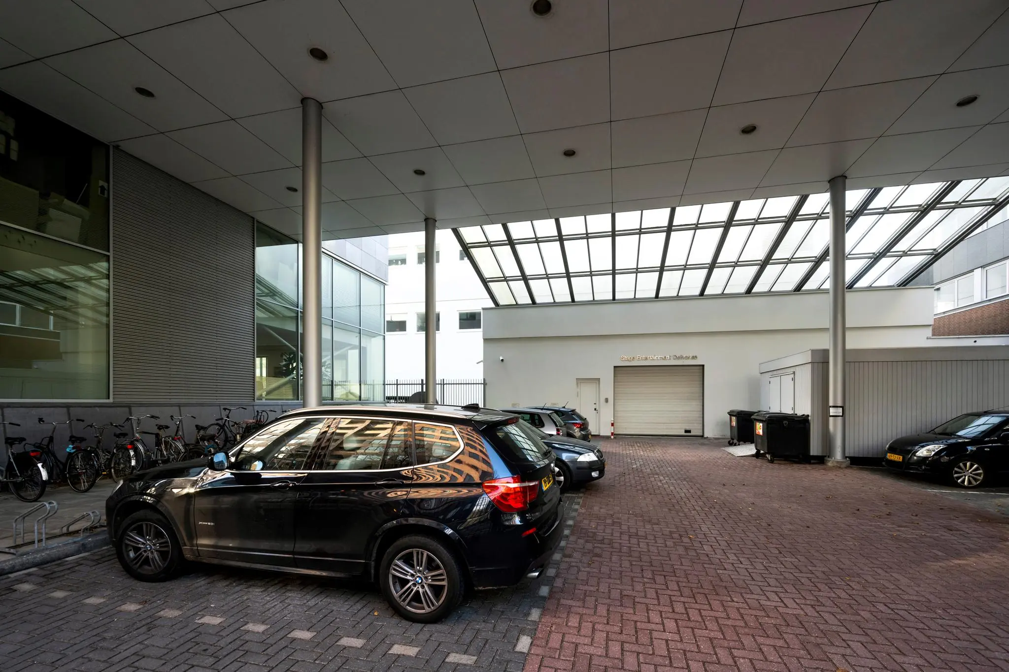 Overdekte parkeerruimte aan de De Boelelaan met geparkeerde auto's, fietsenstalling en een gesloten rolpoort.